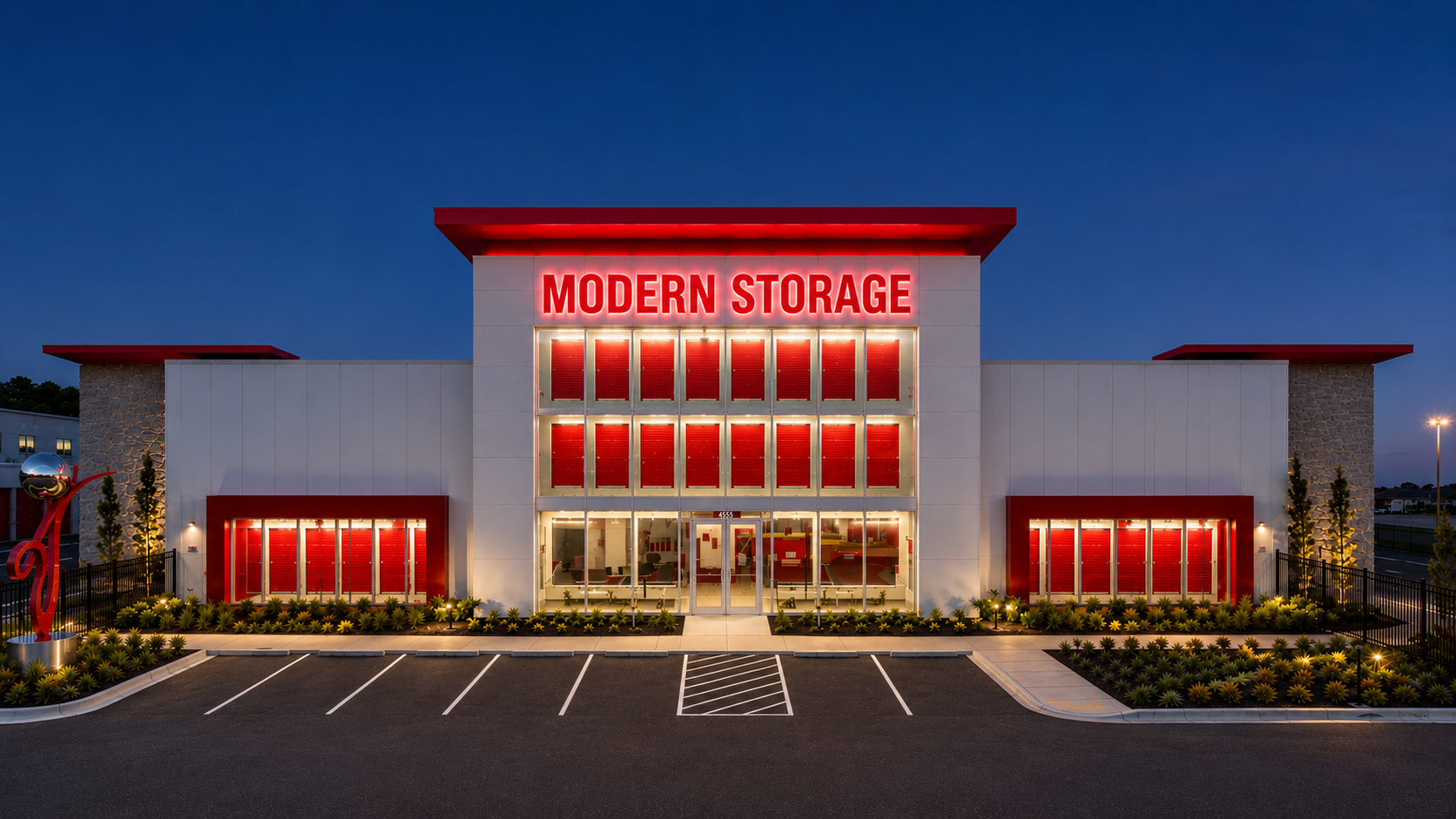 Modern Storage® Lowell Office at Night Front office building at Modern Storage® Lowell illuminated at night with glowing red signage, modern architecture, and landscaped parking area.